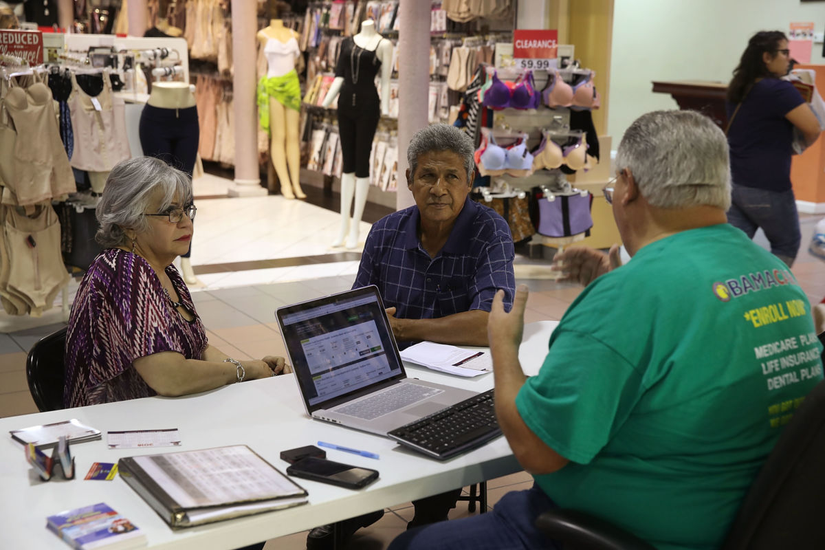 Isabel Diaz Tinoco and Jose Luis Tinoco speak with Otto Hernandez, an insurance agent from Sunshine Life and Health Advisors, as they shop for insurance under the Affordable Care Act at a store set up in the Mall of the Americas on November 1, 2017, in Miami, Florida.