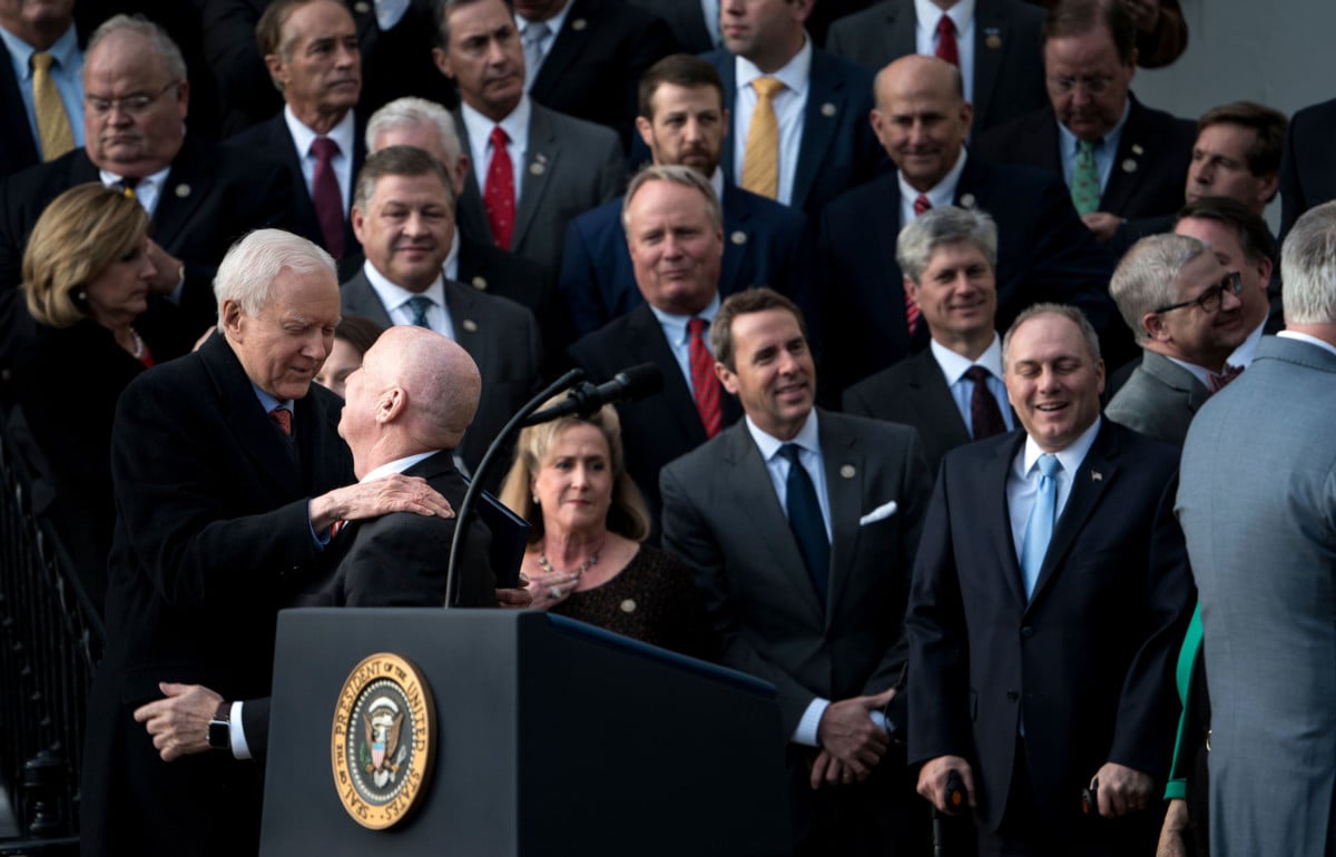 Sen. Orrin Hatch (left) and Rep. Kevin Brady (second left) hug while waiting for President Trump to speak about newly passed tax reform legislation during an event on December 20, 2017, in Washington, DC.