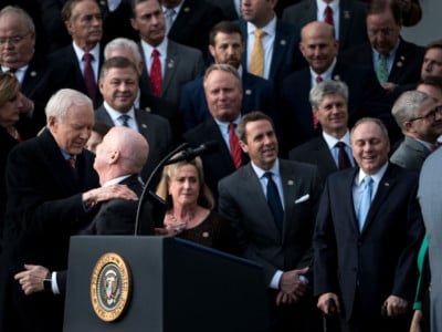 Sen. Orrin Hatch (left) and Rep. Kevin Brady (second left) hug while waiting for President Trump to speak about newly passed tax reform legislation during an event on December 20, 2017, in Washington, DC.