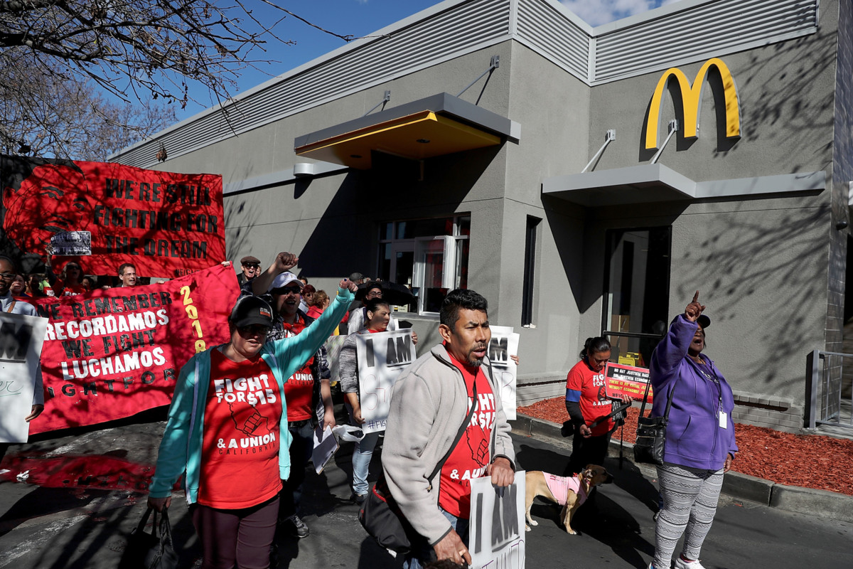 Fast food workers and union members carry signs as they stage a protest outside of a McDonald's restaurant on February 12, 2018, in Oakland, California.