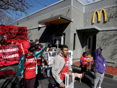 Fast food workers and union members carry signs as they stage a protest outside of a McDonald's restaurant on February 12, 2018, in Oakland, California.