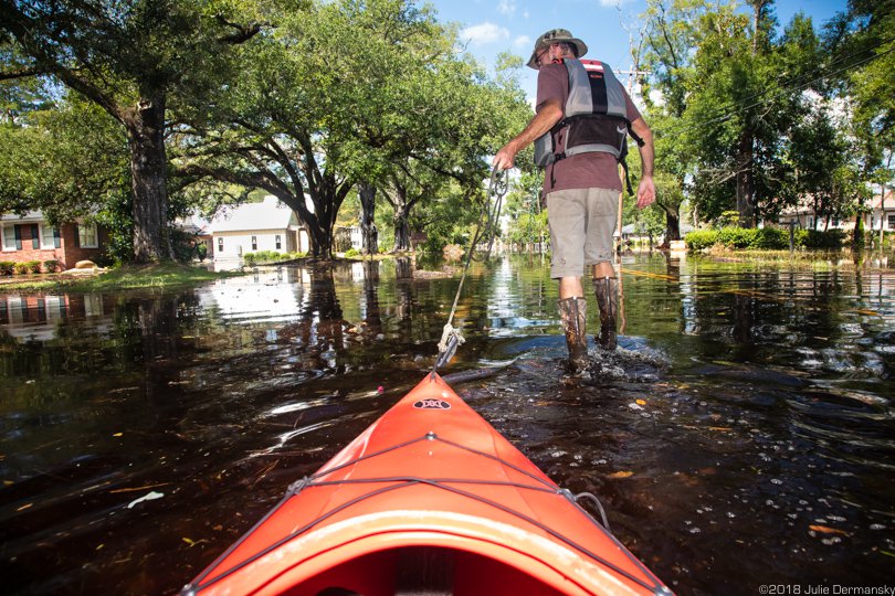Chris Ochsenbein pulling a kayak into floodwater in Conway, South Carolina’s Sherwood neighborhood.