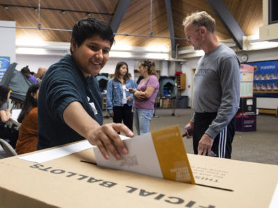 A poll worker puts a mail-in ballot in the box at Deerfield Elementary School in Irvine, California, on November 6, 2018.