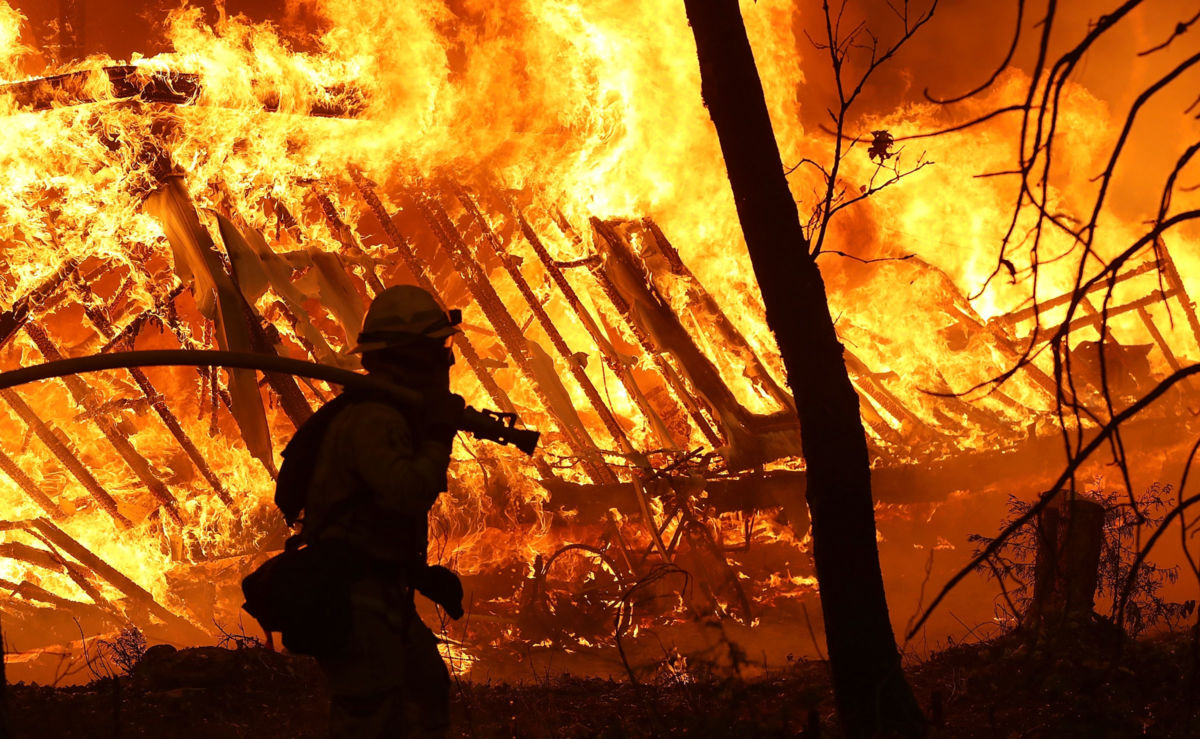 A Cal Fire firefighter monitors a burning home as the Camp Fire moves through the area on November 9, 2018, in Magalia, California.