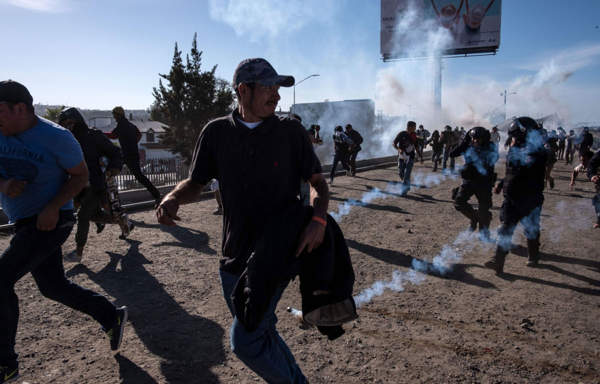 Central American migrants run along the Tijuana River near the El Chaparral border crossing in Tijuana, Mexico, after the US border patrol threw tear gas from a distance to disperse them on November 25, 2018.