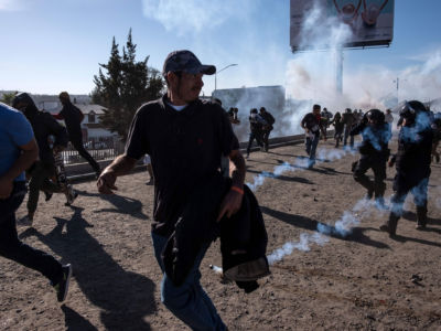 Central American migrants run along the Tijuana River near the El Chaparral border crossing in Tijuana, Mexico, after the US border patrol threw tear gas from a distance to disperse them on November 25, 2018.