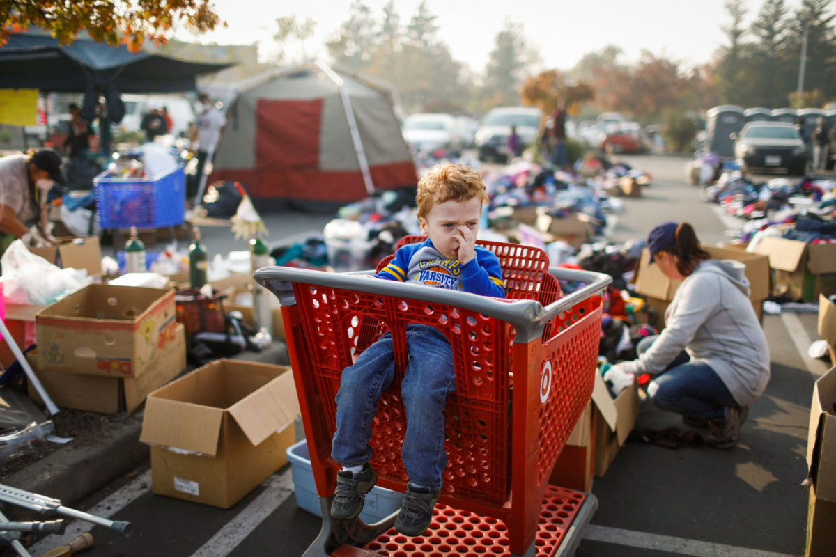 Evacuee Josaiah Darby, 3, waits in a shopping cart as his mother, Autumn Darby, looks through items at a Target parking lot on November 18, 2018. Autumn and her son Josaiah lost their home after the Camp Fire tore through Paradise, California. Tens of thousands have been left homeless after the fire burned through the town and other communities east of Chico.