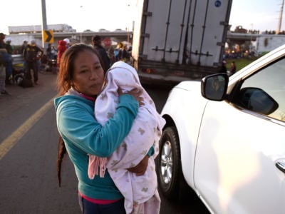 A woman taking part in a caravan of migrants from poor Central American countries carries a baby as she waits along the Irapuato-Guadalajara highway in the Mexican state of Guanajuato on November 12, 2018.