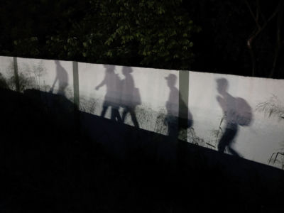 Shadows are reflected on a wall as members of the Central American migrant caravan moves in the pre-dawn hours on November 2, 2018, in Matias Romero, Mexico.