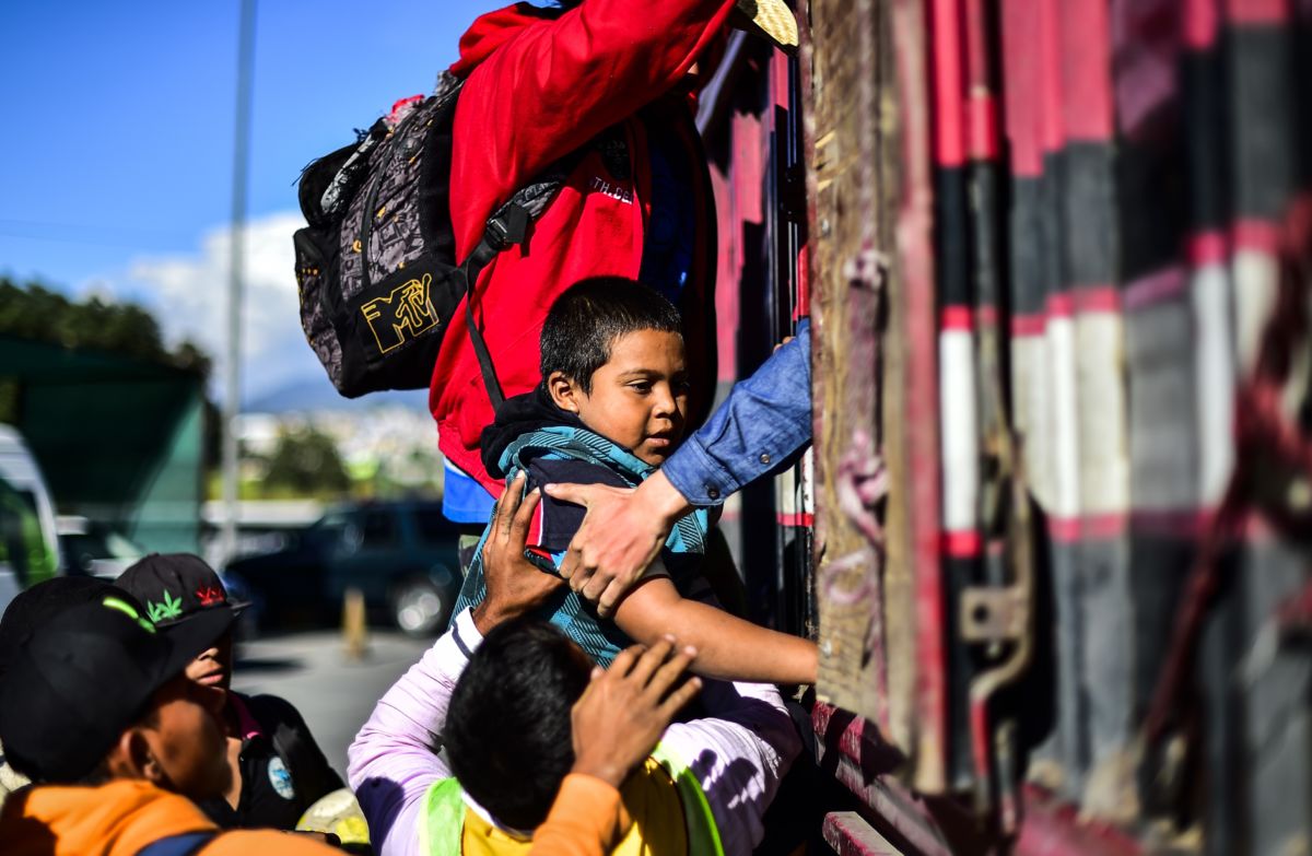 A boy receives help to get into the back of a truck as migrants from poor Central American countries -mostly Hondurans- move toward the United States in hopes of a better life or to escape violence are offered a ride along the Mexico City-Puebla highway in San Marcos, Mexico, on November 5, 2018.