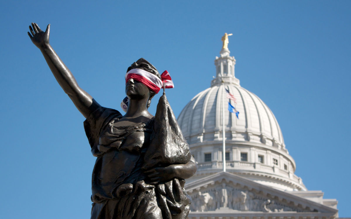 A flag is fashioned into a blindfold and placed around the eyes of Forward, the statue on the stairway leading to the capitol from State Street in Madison, Wisconsin, during a 2011 protest against Scott Walker's anti-labor budget repair bill.