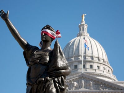A flag is fashioned into a blindfold and placed around the eyes of Forward, the statue on the stairway leading to the capitol from State Street in Madison, Wisconsin, during a 2011 protest against Scott Walker's anti-labor budget repair bill.