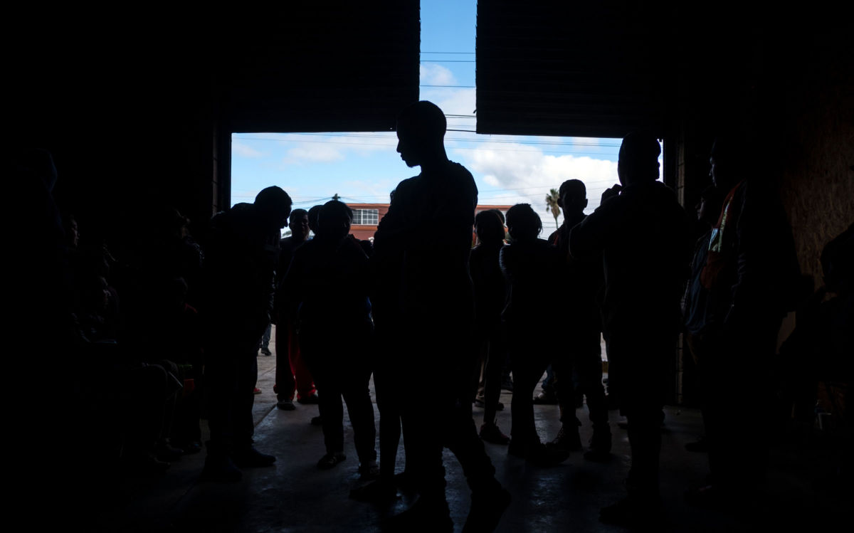 Central American migrants who travelled in a caravan to the Mexico-US border gather at the entrance of a temporary shelter in downtown Tijuana, Baja California State, Mexico, on December 17, 2018.