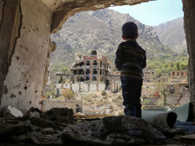 A Yemeni child looks out at buildings that were damaged in an air strike in the southern Yemeni city of Taez, March 18, 2018.