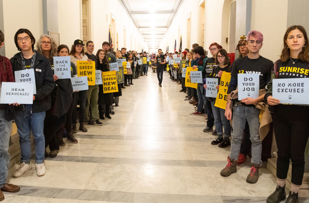 Protesters hold placards urging Democrats to support the Green New Deal inside the office of Nancy Pelosi at the US Capitol in Washington, DC.