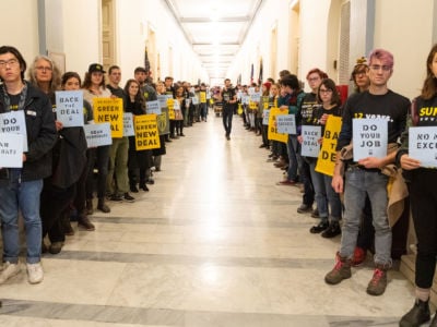 Protesters hold placards urging Democrats to support the Green New Deal inside the office of Nancy Pelosi at the US Capitol in Washington, DC.