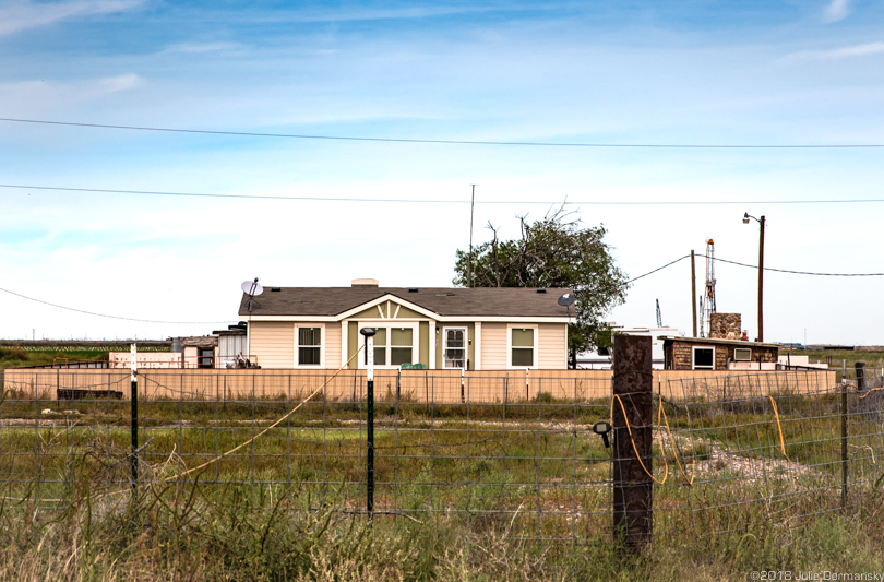 The Franklins’ home with a drilling rig at a frack site behind it.