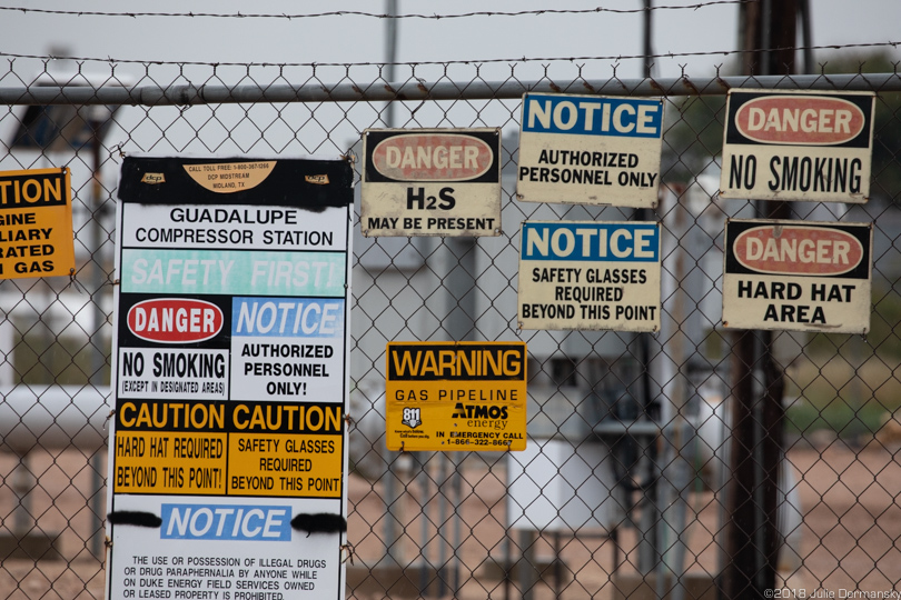 Warning signs on a fracking industry site’s fence in the Permian Basin.