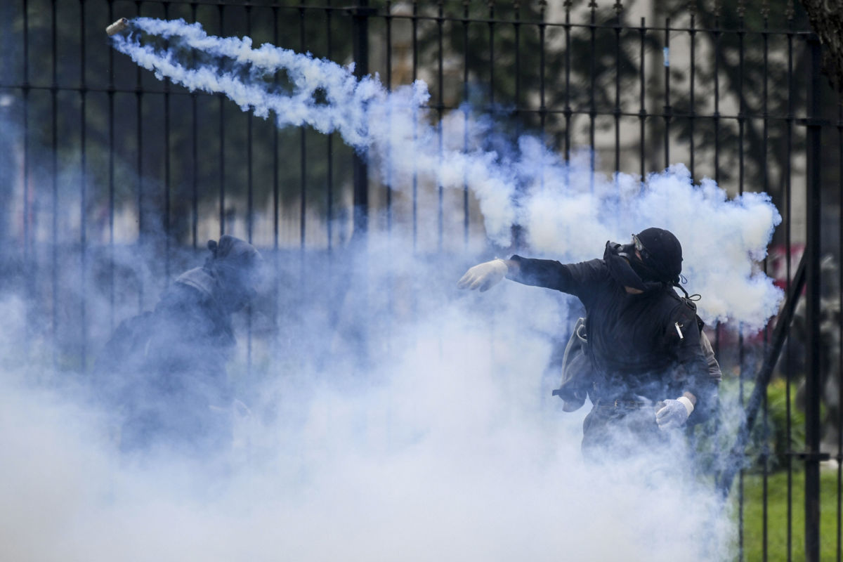 A demonstrator throws a tear gas canister back at police outside the Argentine Congress as deputies began discussion on the government's austere 2019 budget in Buenos Aires, Argentina, on October 24, 2018.