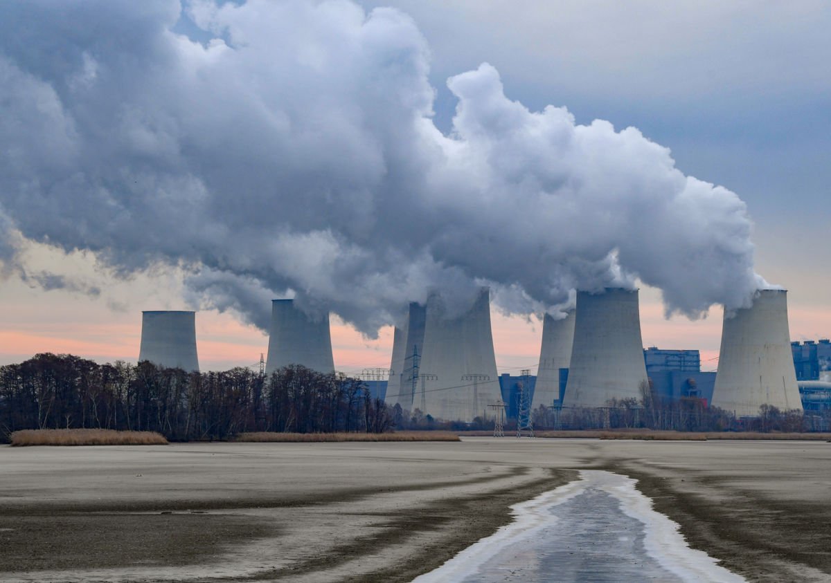 Behind a drained carp pond, water vapor rises from the cooling towers of the Jänschwalde lignite-fired power plant of the Lausitz Energie Bergbau AG into the murky morning sky in Peitz, Germany, on November 30, 2018.