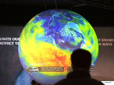 People watch the Earth globe at the COP21, the United Nations conference on climate change, in Le Bourget on December 10, 2015.