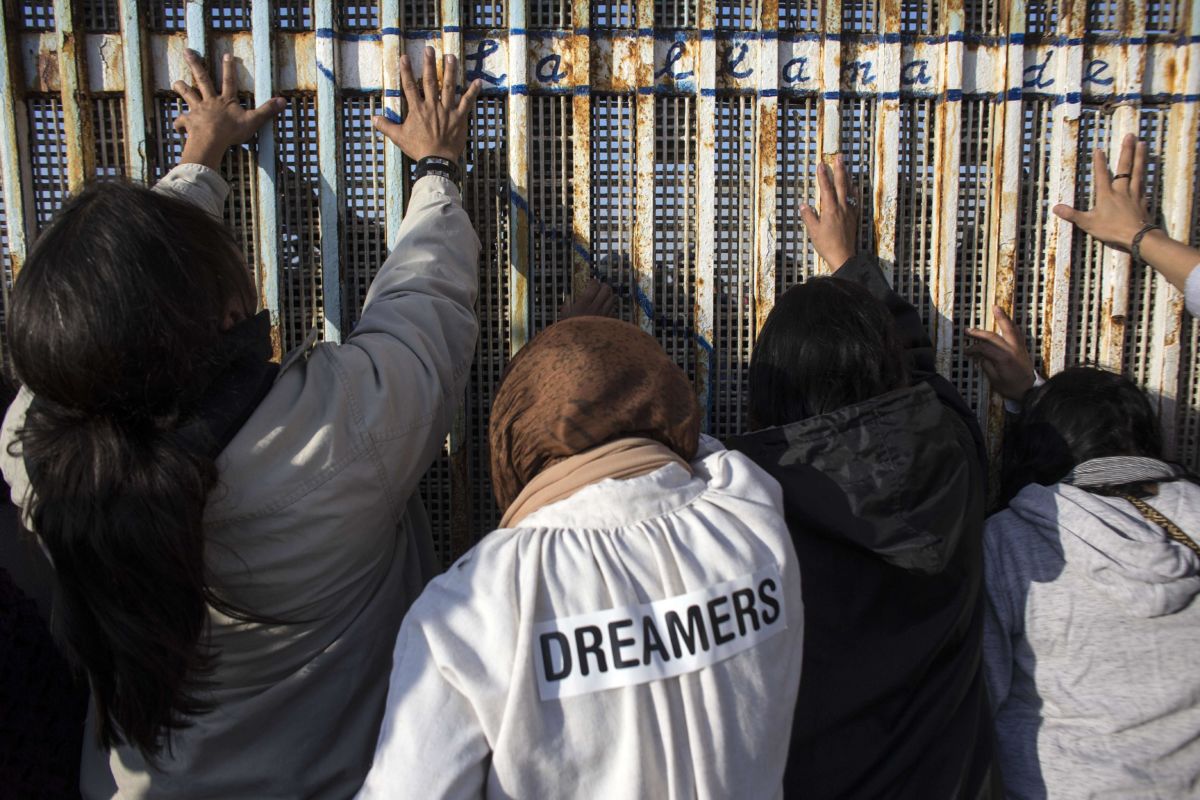 People gather on the Mexican side of the border fence to touch hands during the celebration of the Posada Sin Fronteras or Posada Without Borders at the Mexican-US border on December 16, 2017, as part of the Christmas celebrations in Playas de Tijuana, northwestern Mexico.