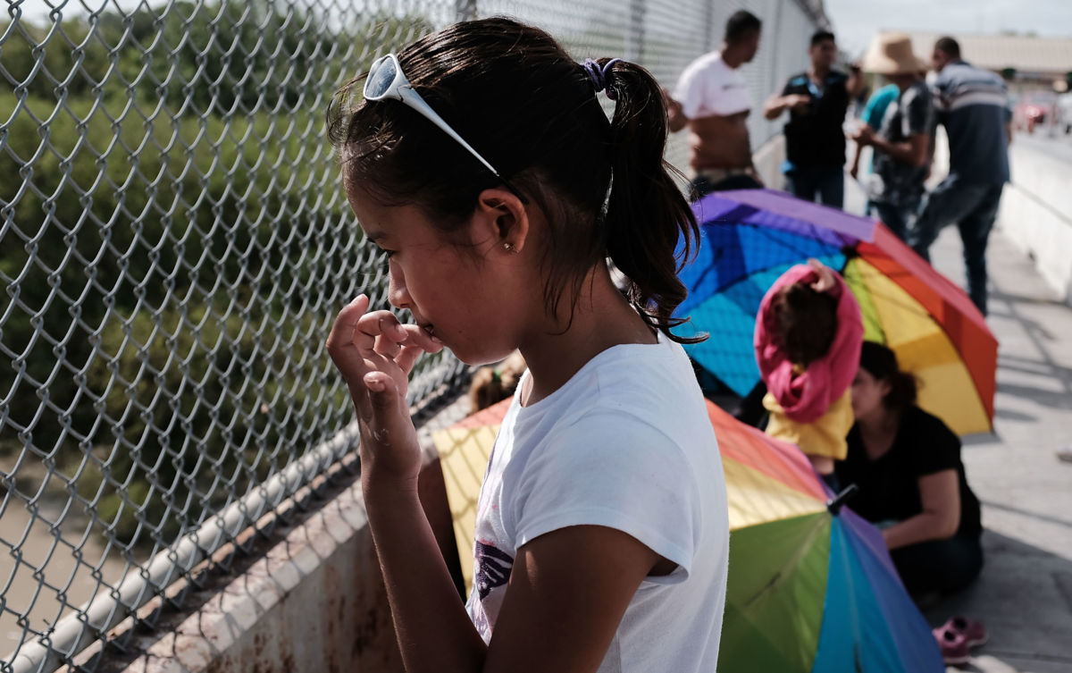 A Honduran child waits with her family along the border bridge after being denied entry from Mexico into the US on June 25, 2018, in Brownsville, Texas.