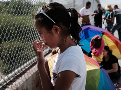 A Honduran child waits with her family along the border bridge after being denied entry from Mexico into the US on June 25, 2018, in Brownsville, Texas.