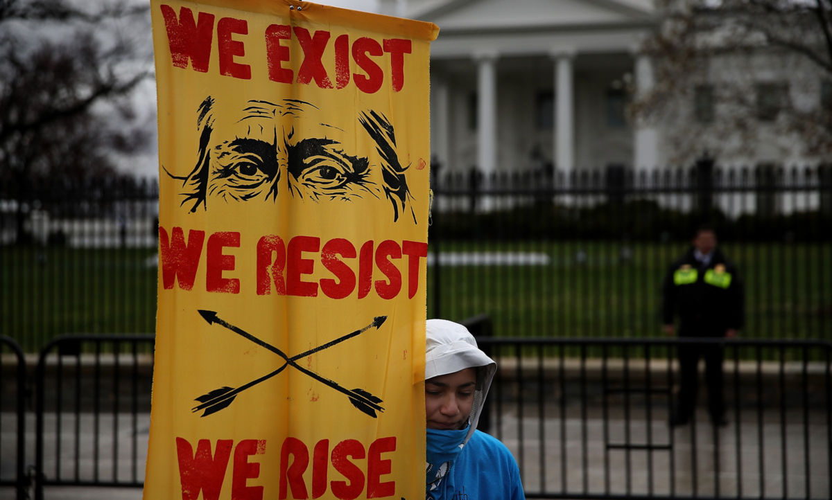 A protester holds a sign in front of the White House during a demonstration on March 10, 2017, in Washington, DC. The lack of treaty-guaranteed essential services has put Indigenous lives in peril.