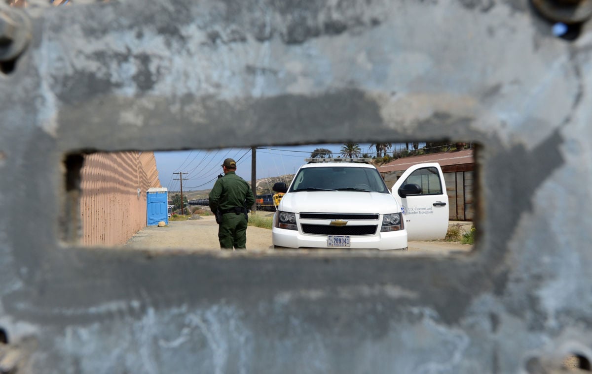 A US Border Patrol agent, seen through an opening in a fence, keeps watch near the San Ysidro port of entry along the US-Mexico border near San Diego, California on April 4, 2013.