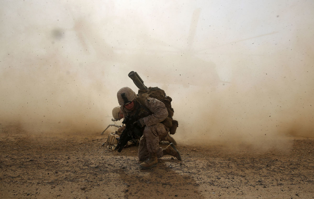 A US marine shields himself from dust being kicked up from a helicopter lifting off April 28, 2014, during a mission in Helmand Province, Afghanistan.