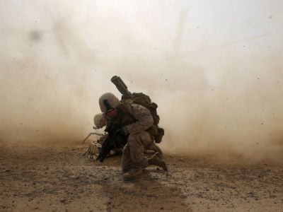 A US marine shields himself from dust being kicked up from a helicopter lifting off April 28, 2014, during a mission in Helmand Province, Afghanistan.