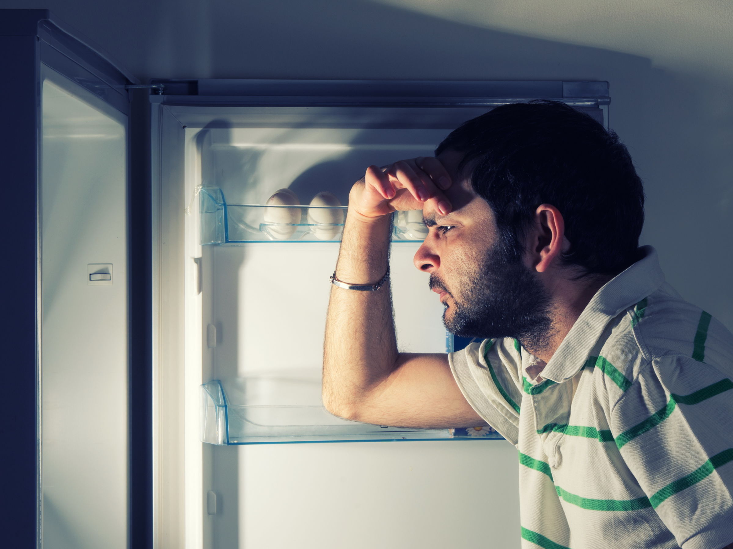 Человек смотрит в холодильник