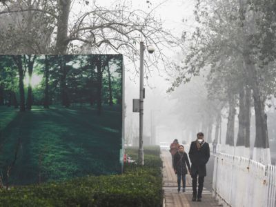 Pedestrians walk past a billboard scene of green trees and grass on a heavily polluted day in Beijing, China, on December 1, 2015.
