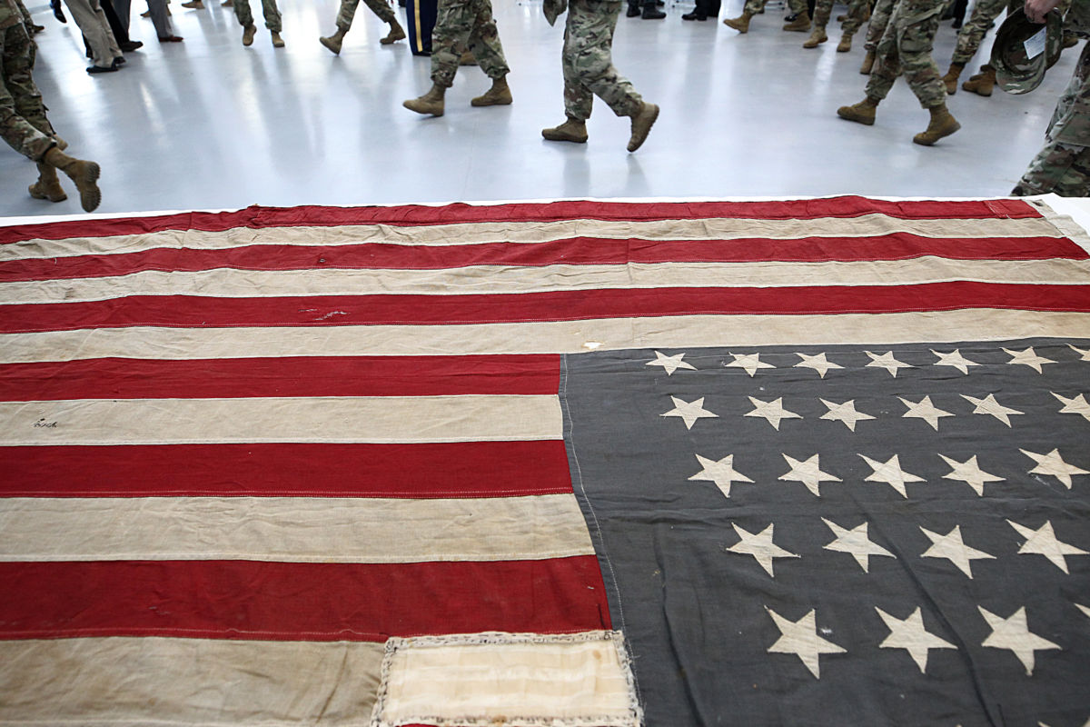 National Guard soldiers walk past a flag in the newly remodeled National Guard Armory in Natick, Massachusetts, on October 26, 2018. National Guard members are now deployed in at least 56 countries around the world.