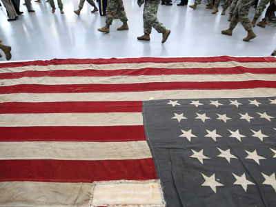 National Guard soldiers walk past a flag in the newly remodeled National Guard Armory in Natick, Massachusetts, on October 26, 2018. National Guard members are now deployed in at least 56 countries around the world.