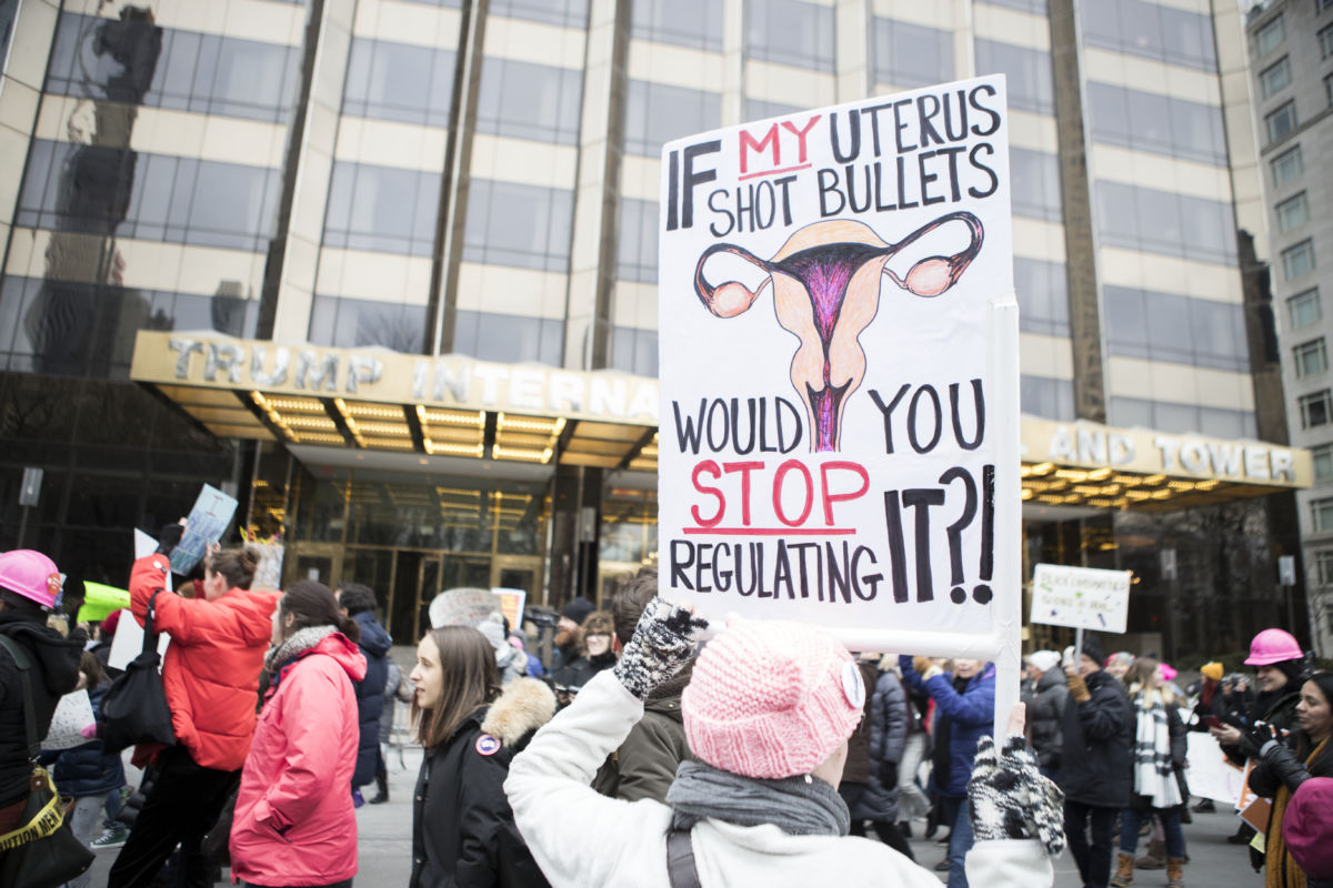 A marcher holds a sign that says "If My Uterus Shot Bullets Would You Stop Regulating It?!" in front of Trump International Hotel during the Women's March in the borough of Manhattan in NY on January 19, 2019.