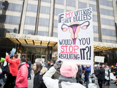 A marcher holds a sign that says "If My Uterus Shot Bullets Would You Stop Regulating It?!" in front of Trump International Hotel during the Women's March in the borough of Manhattan in NY on January 19, 2019.