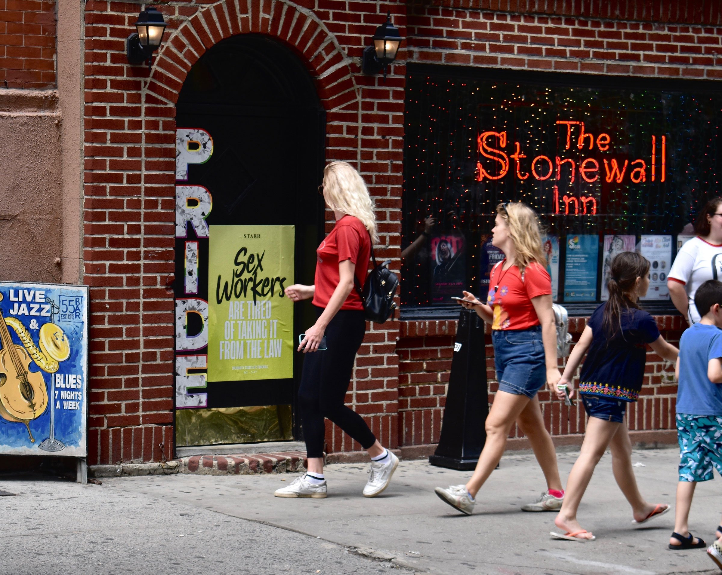 Pedestrians walk by a poster supporting sex workers displayed at The Stonewall Inn.