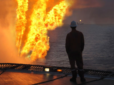Workers stands by flare on offshore oil drilling rig.