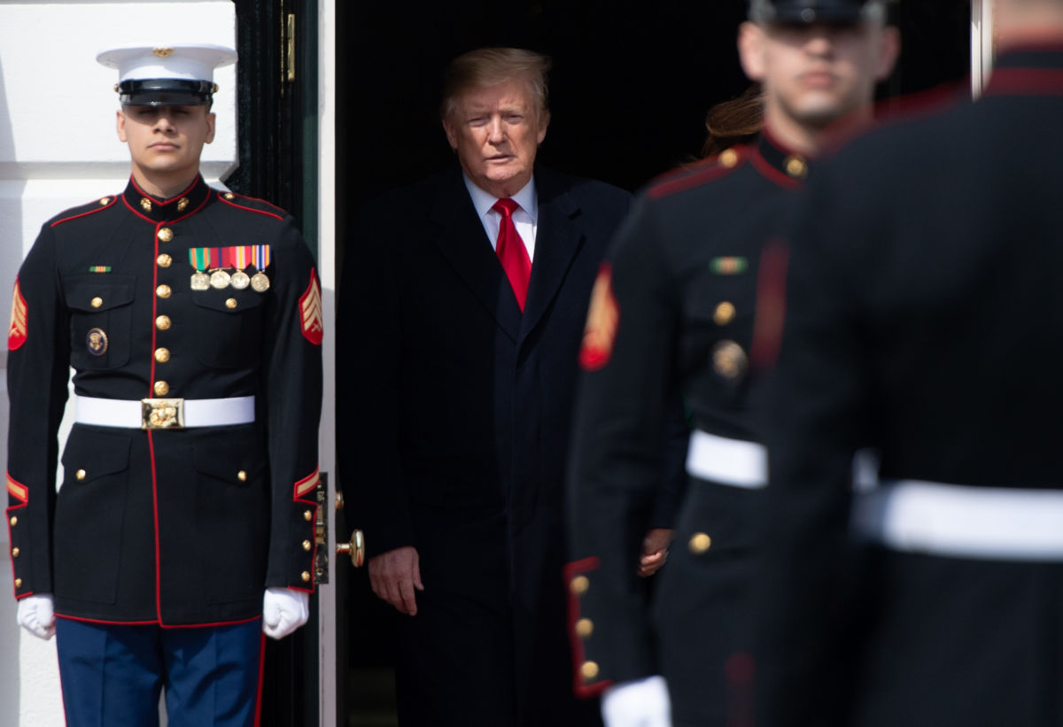 Flanked by officers, donald trump hides in a shadowy doorway
