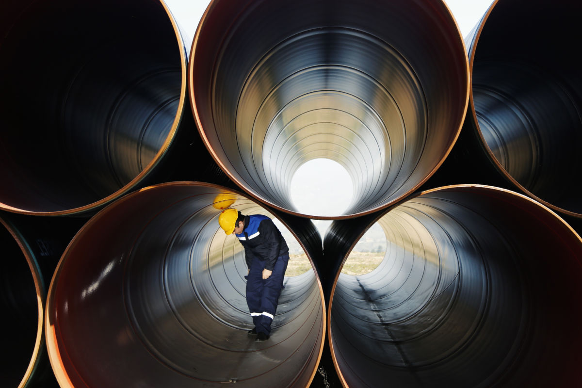 Worker stands inside of large industrial pipe