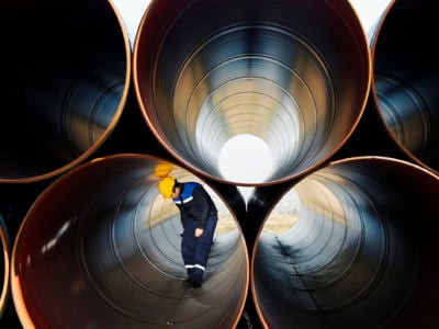 Worker stands inside of large industrial pipe