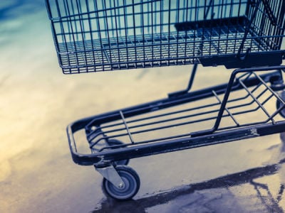 An empty shopping cart stands in parking lot