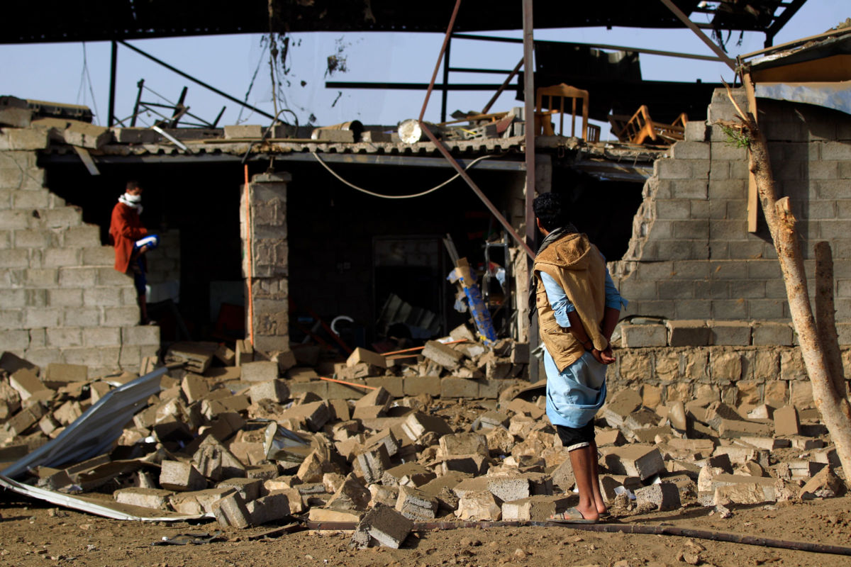 Man stands amid the rubble from airstrike in Yemen.