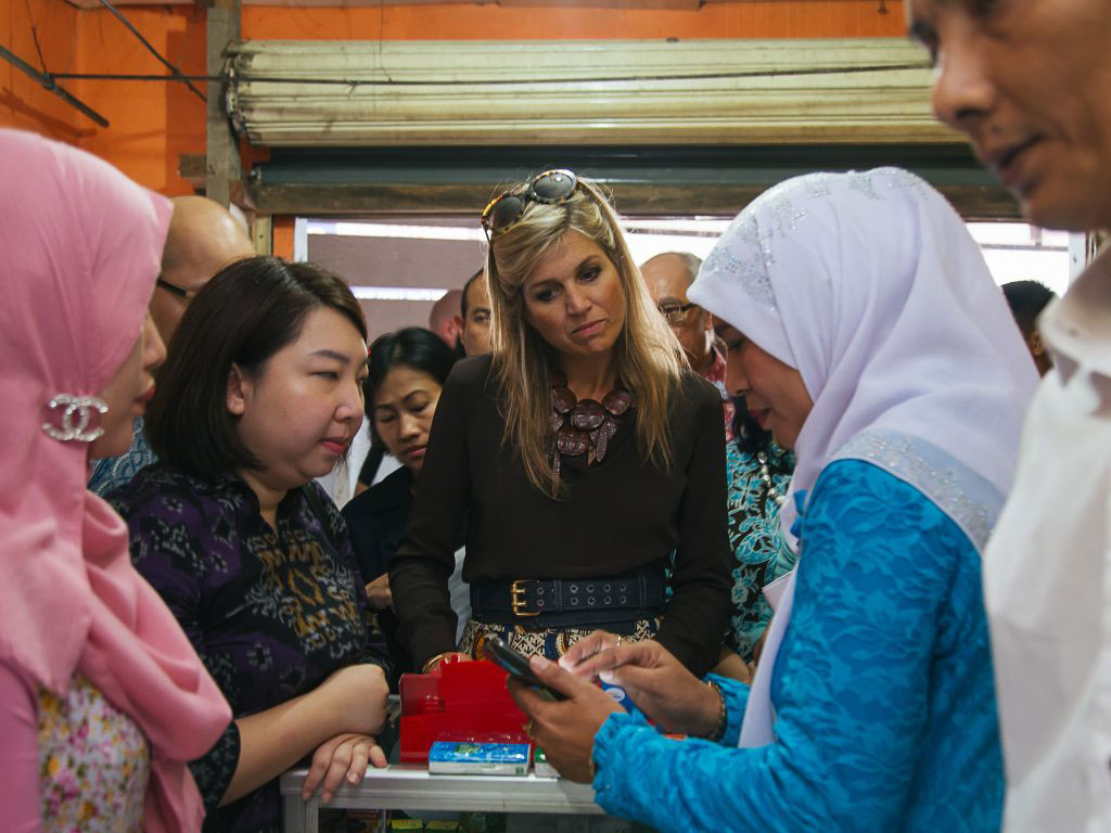 In a small shop in Jakarta, a woman demonstrates to the UN Special Advocate for Inclusive Finance how digital payments work.