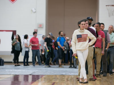 Woman in a US flag sweater stands at the front of a long line of waiting voters