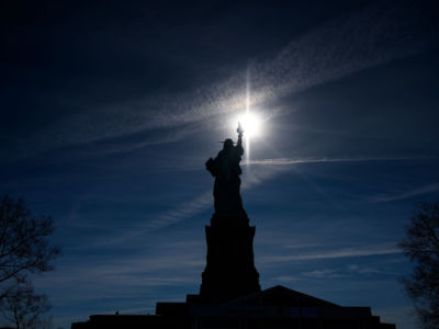 The Statue of Liberty is backlit by the sun