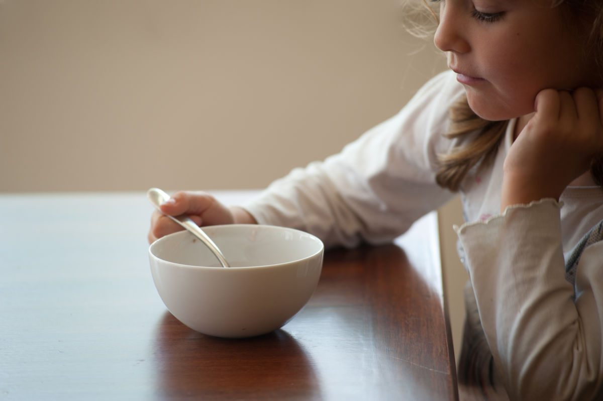 A young girl looks into an empty bowl