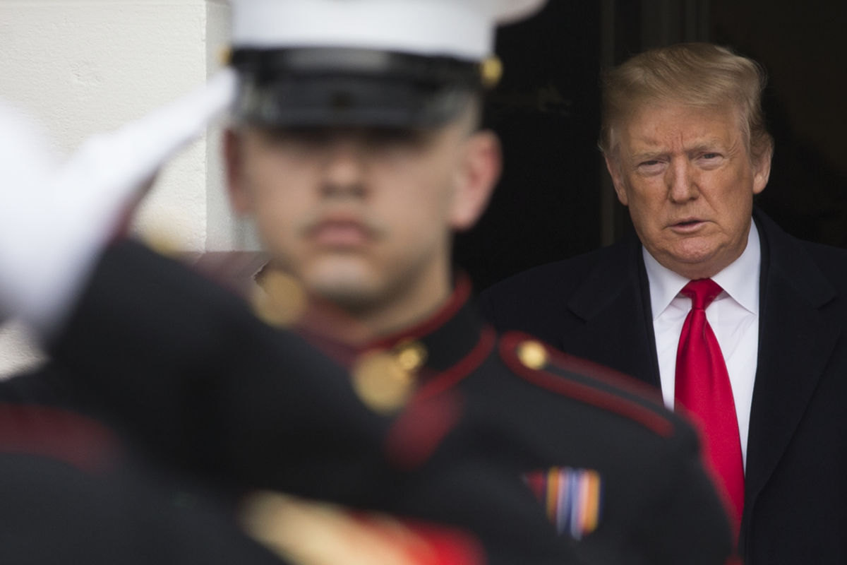 Donald Trump stands in a shadowy doorway